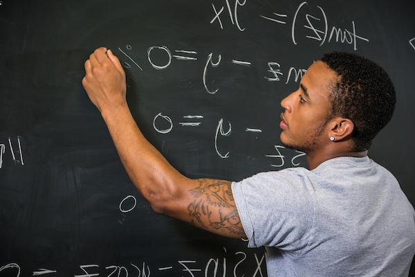 Picture of student writing an equation on chalkboard